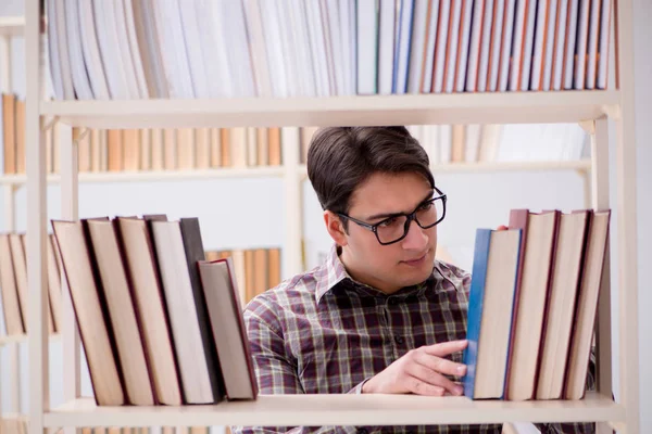 Jovem estudante procurando livros na biblioteca da faculdade — Fotografia de Stock