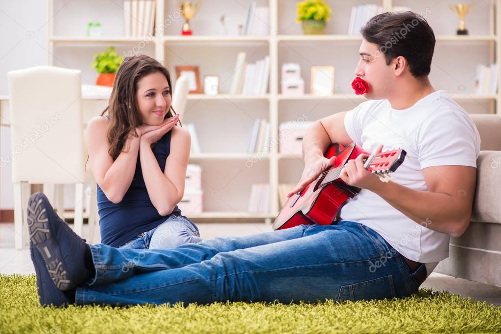 Romantic pair playing guitar on floor