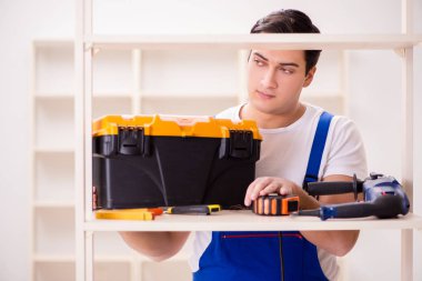 İşçi adam montaj kitaplığını tamir ediyor