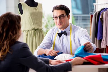 Bayan müşteriyle çalışan genç bir terzi.