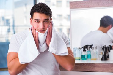 Genç yakışıklı adam yüz kremi sürüyor.