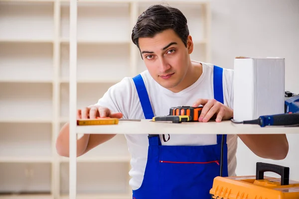 Trabalhador reparando montagem estante de livros — Fotografia de Stock