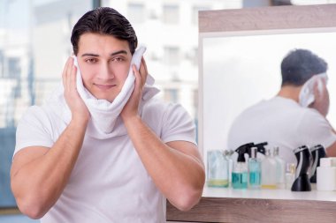 Genç yakışıklı adam yüz kremi sürüyor.