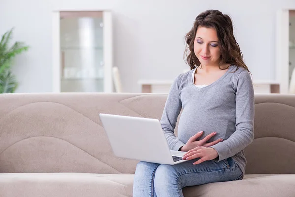 Schwangere arbeitet am Laptop und sitzt auf Sofa — Stockfoto