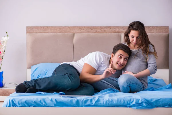 Familia joven con esposa embarazada esperando al bebé en la cama — Foto de Stock