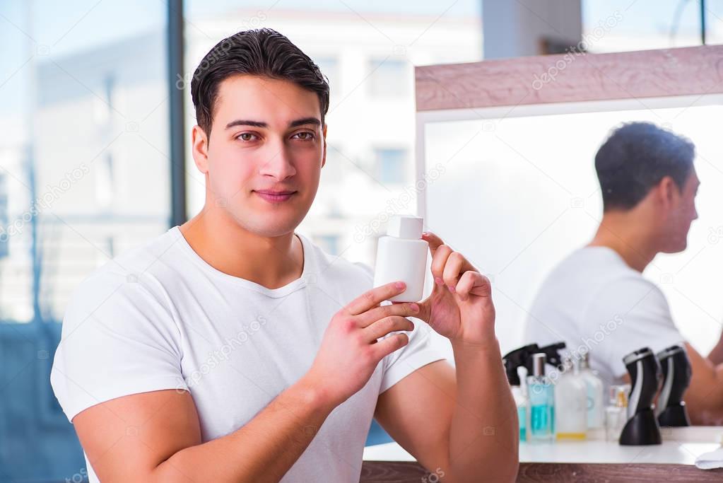 Young handsome man applying face cream