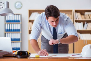 Ofiste çizimler üzerinde çalışan bir mühendis.