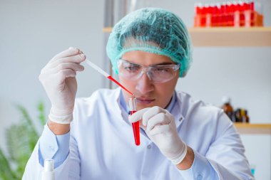 Laboratuvar hastanesinde kan testi üzerinde çalışan genç bir doktor.