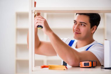 İşçi adam montaj kitaplığını tamir ediyor