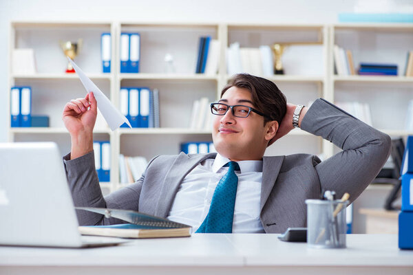 Бизнесмен с бумажным самолетом в офисе