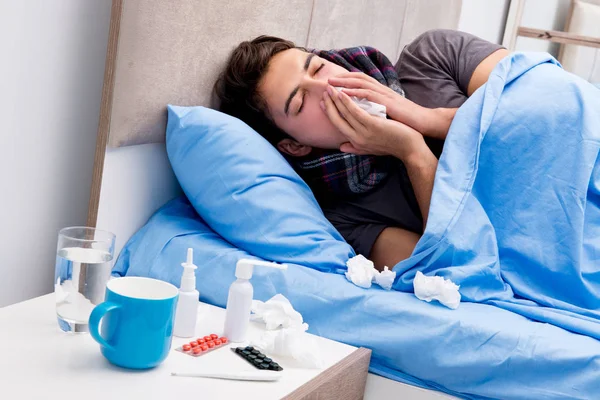 Nemocný muž v posteli brát léky a léky — Stock fotografie