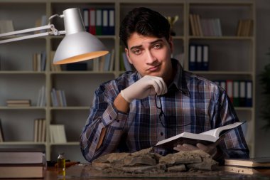 Arkeolog geç saatlere kadar ofiste çalışıyor.