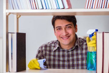 Kitaplıktaki tozları temizleyen adam