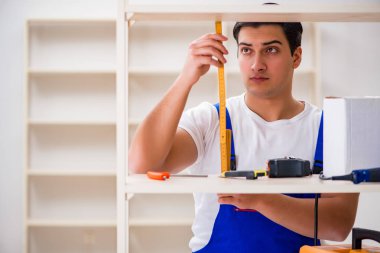 İşçi adam montaj kitaplığını tamir ediyor