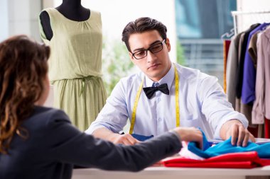 Bayan müşteriyle çalışan genç bir terzi.