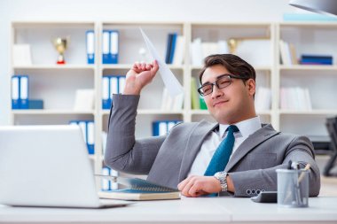 Ofisinde kağıt uçak olan bir iş adamı.