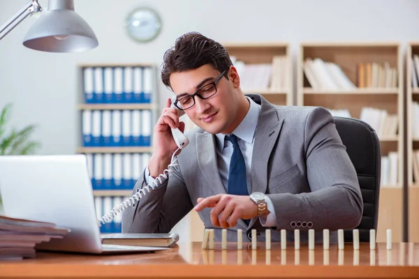 Geschäftsmann mit Dominosteinen im Büro — Stockfoto