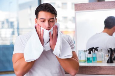 Genç yakışıklı adam yüz kremi sürüyor.