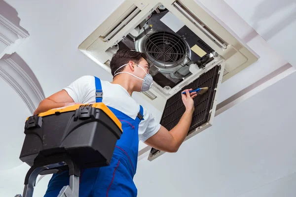 Worker repairing ceiling air conditioning unit — Stock Photo, Image