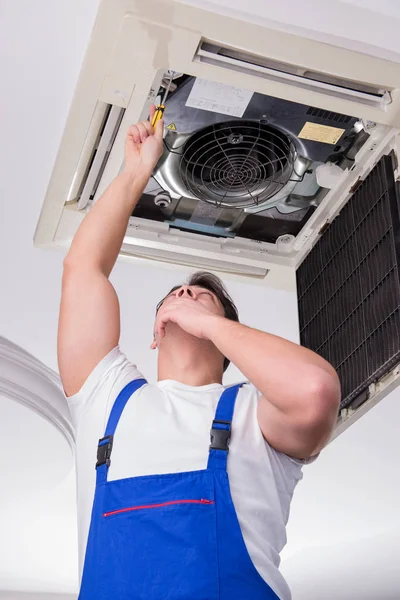 Worker repairing ceiling air conditioning unit