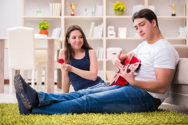 Pareja romántica tocando la guitarra en el suelo — Foto de Stock