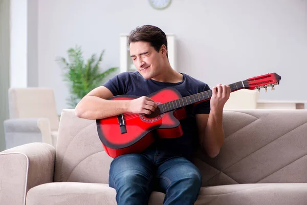 Giovane uomo che pratica la chitarra a casa — Foto Stock