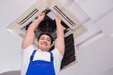 İşçi tavan havalandırma ünitesini tamir ediyor