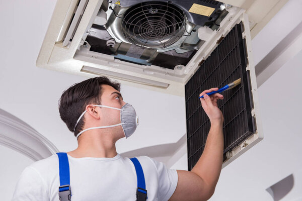 Worker repairing ceiling air conditioning unit