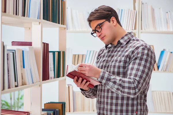 Jeune étudiant à la recherche de livres dans la bibliothèque du collège — Photo