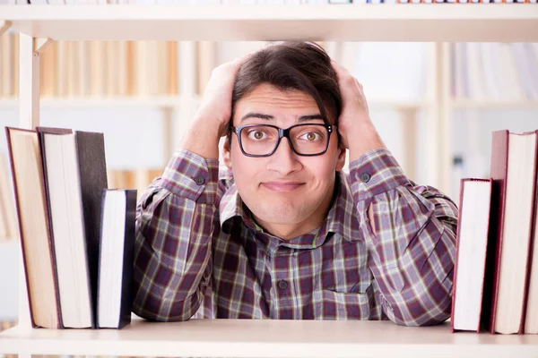 Jonge student op zoek naar boeken in universiteitsbibliotheek — Stockfoto