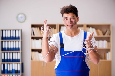 Kablolara dolanmış komik genç elektrikçi.