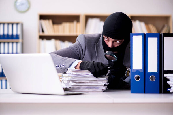 Criminal businessman wearing balaclava in office