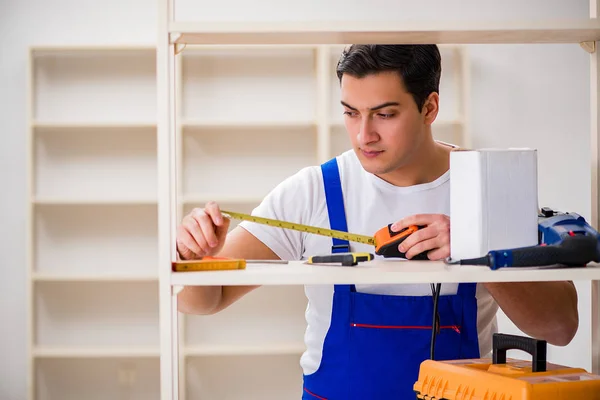 Arbeiter repariert Bücherregal — Stockfoto