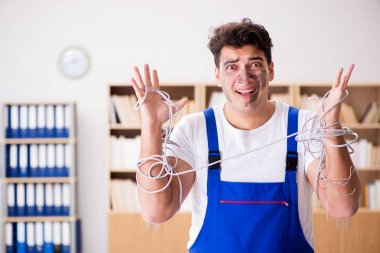 Kablolara dolanmış komik genç elektrikçi.