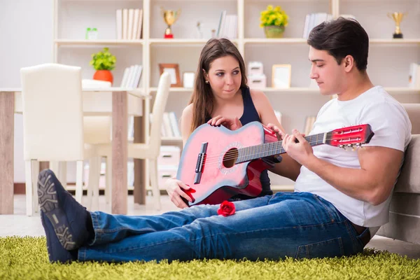 Pareja romántica tocando la guitarra en el suelo — Foto de Stock