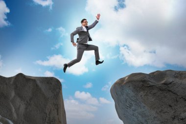 Ambitious businessman jumping over the cliff clipart
