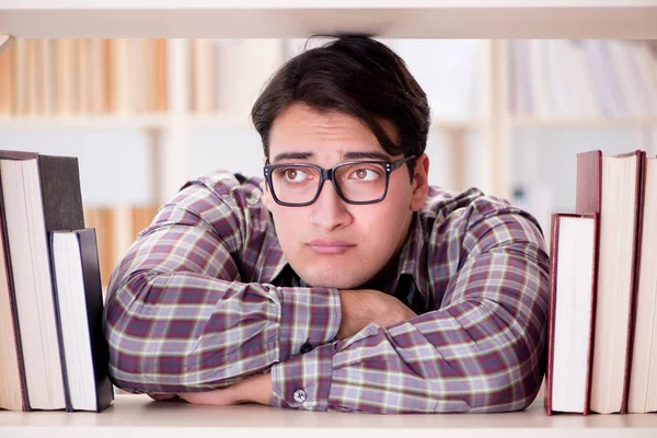 Jeune étudiant à la recherche de livres dans la bibliothèque du collège — Photo