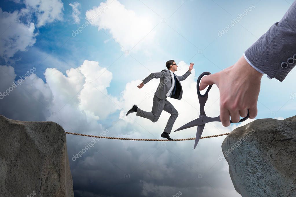 Hand cutting the rope under businessman tightrope walker