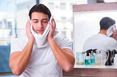 Genç yakışıklı adam yüz kremi sürüyor.