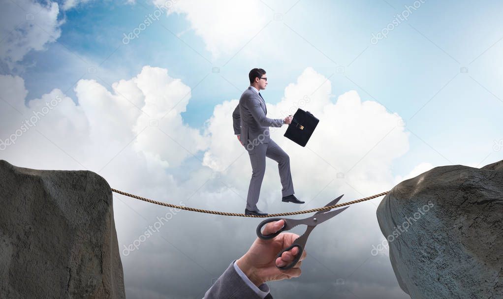 Hand cutting the rope under businessman tightrope walker