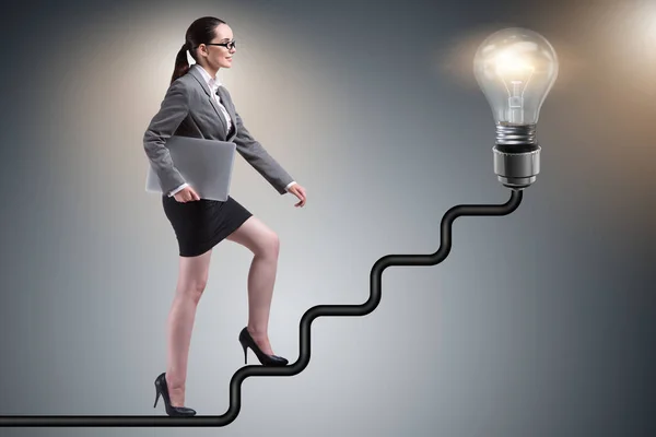 Businesswoman climbing career ladder towards light bulb — Stock Photo, Image