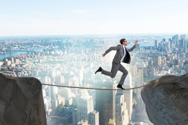İş adamı iş konseptinde sıkı bir ipin üzerinde yürüyor