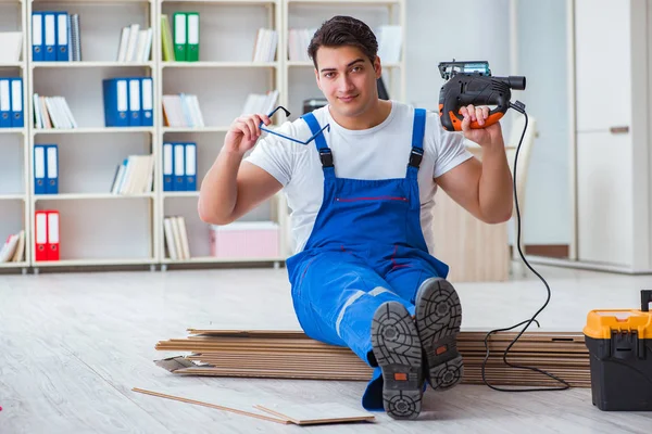 Ung arbejdstager, der arbejder på gulv laminat fliser - Stock-foto