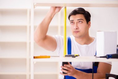 İşçi adam montaj kitaplığını tamir ediyor