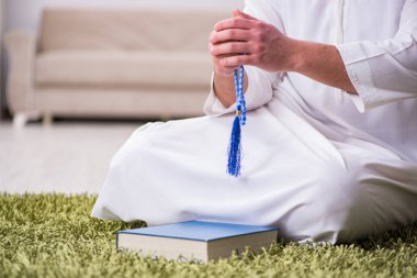 Arap adam evde dua ediyor.