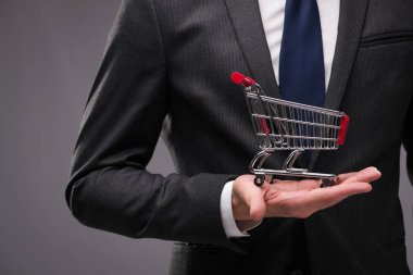 Gri arka plan üzerinde alışveriş sepeti ile işadamı