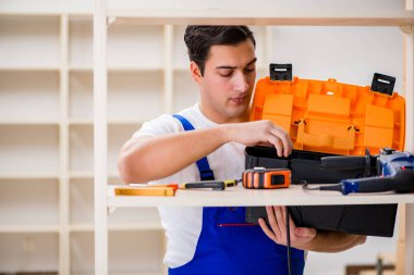 İşçi adam montaj kitaplığını tamir ediyor