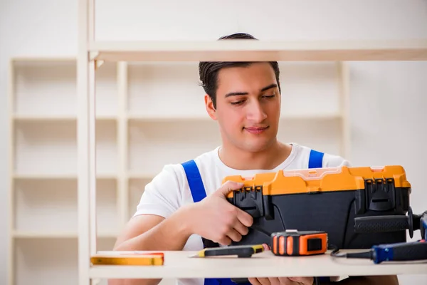 Trabalhador reparando montagem estante de livros — Fotografia de Stock