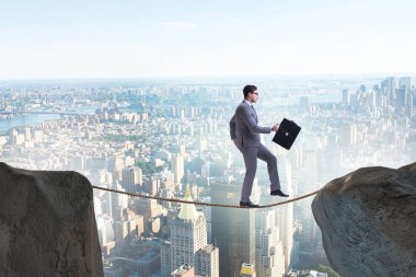 İş adamı iş konseptinde sıkı bir ipin üzerinde yürüyor