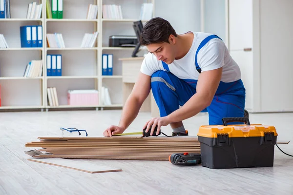 Trabajador joven que trabaja en baldosas laminadas piso — Foto de Stock